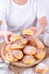 Homemade Hot buns with raisins on a wooden board. The child holds a bun in his hands
