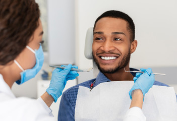 Smiling guy in dentist chair looking with trust at doctor