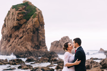 newlyweds hug and look at each other on the background of stones