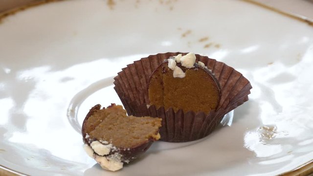 Chocolate candies on a white saucer. Confectionery. Selective focus. Chocolate candies without a wrapper on a light background. Tasty sweets for tea on a white porcelain saucer. Traditional sweets.
