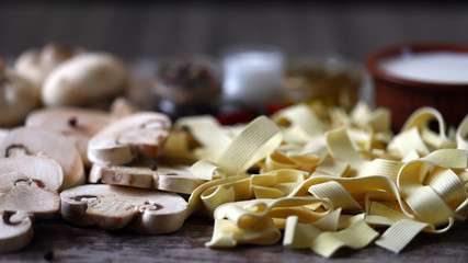 Raw pasta, mushrooms, cream, spices. The recipe for pasta with mushrooms. Cooking at home.