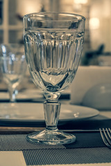 : The served table in the restaurant. Clean dishes and appliances on the tablecloth in a cafe. Shiny transparent glasses. White plates. Prepared for the reception of guests. High service.