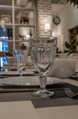 : The served table in the restaurant. Clean dishes and appliances on the tablecloth in a cafe. Shiny transparent glasses. White plates. Prepared for the reception of guests. High service.