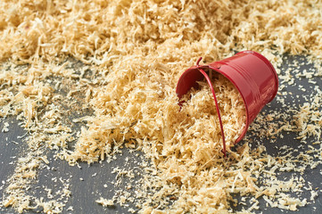 Wooden sawdust in red metal bucket in carpentry workshop © OlekStock