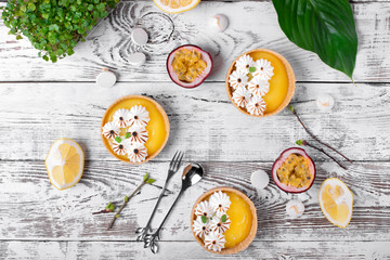 Mini tarts with lemon curd and caramelized meringue on the white wooden table. Top view. Copy space