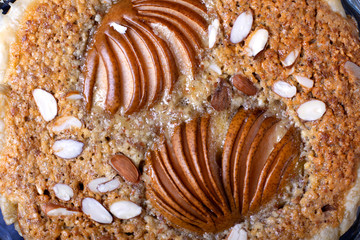 Puff pastry pie with pear and almond in a glass baking dish on the grey table