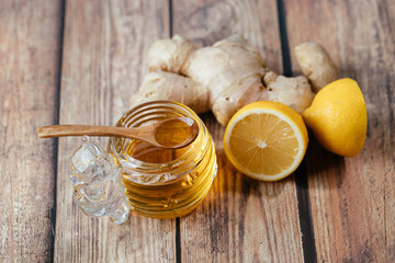 Honey in a jar, sliced lemon and ginger. Wood background. Flat lay. Top view. Close up.