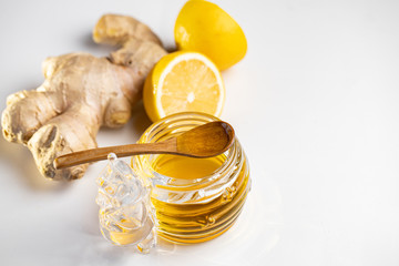 Honey in a jar, sliced lemon and ginger. White background. Flat lay. Close up. Top view.