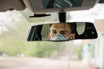 a male driving car wearing protective face mask and gloves