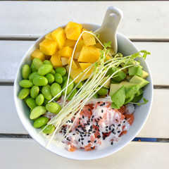 top view on a poke bowl with raw salmon, avocado, mango, green beans and bean sprouts