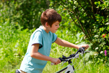 Fototapeta na wymiar Handsome young boy on a bicycle on a beautiful sunny summer day
