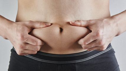 Naklejka premium Man touches his fat belly closeup, obesity, male weight loss and diet concept