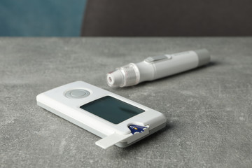 Blood glucose meter on gray table, close up