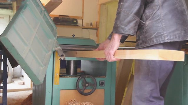 Carpenter is straightens the board's, plank surface on machine, to make them in parallel.