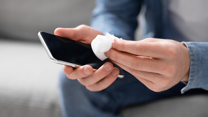 Man disinfecting his cell phone with antibacterial napkins