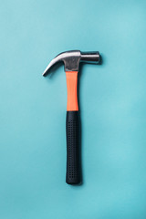 metal hammer with an orange handle on a blue background close