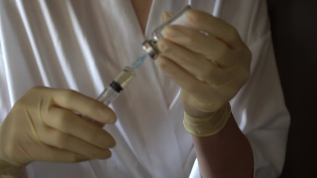 Self-injection of antibiotics. Female preparing needle for injecting her buttocks. Woman injecting buttocks.