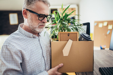Losing job. Sad quiet man looking frustrated while coming home with a heavy box full of personal...