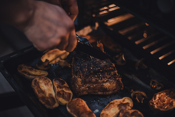 Man cut pork belly, potatoes on baking tray cooked in oven. Traditional country cuisine. Baked fat meat. Cooked meal. Home made handmade food. Rustic style. Gastronomy concept. Appetizing dinner