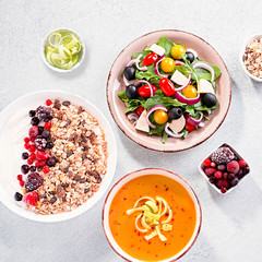 Carrot cream soup, Greek salad, granola bowl with yogurt on concrete table top with copy space. Assortment of dishes for diet, suitable for volumetrics diet and other nutrition strategies, top view