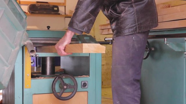 Carpenter is straightens the board's, plank surface on machine, to make them in parallel.