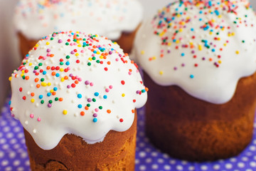 Easter cakes on a purple background close-up. Cakes with white glaze and colored design. A few cakes in the frame.