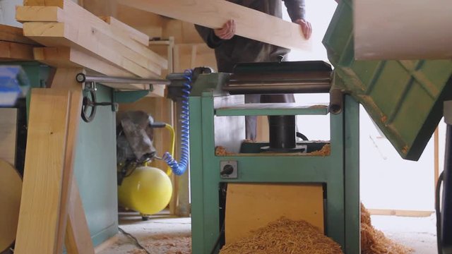 Carpenter is straightens the board's, plank surface on machine, to make them in parallel.