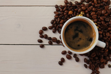 Cup with tasty coffee and roasted grains on wooden table
