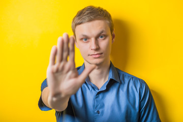 Handsome young man holding his hand, showing the stop. Close portrait. stop, stop gesture. Isolated...
