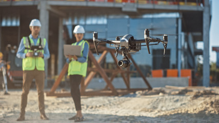 Diverse Team of Specialists Pilot Drone on Construction Site. Architectural Engineer and Safety...