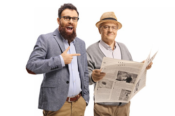 Bearded man laughing and pointing at an elderly man with a newspaper
