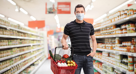 Young man with a medical mask and a shopping basket in a supermarket