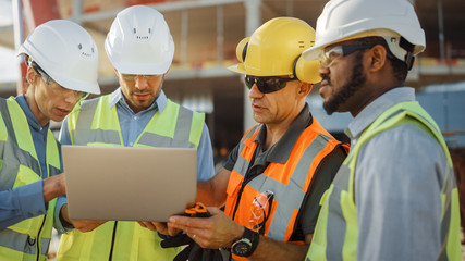 Diverse Team of Specialists Use Laptop Computer on Construction Site. Real Estate Building Project...