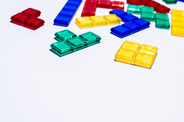 Colorful mixed square blocks on white background, high contrast colours, red blue yellow and green transparent tiles, game for kids, copy space, plenty of text room