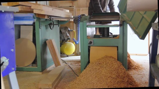 Carpenter is straightens the board's, plank surface on machine, to make them in parallel.