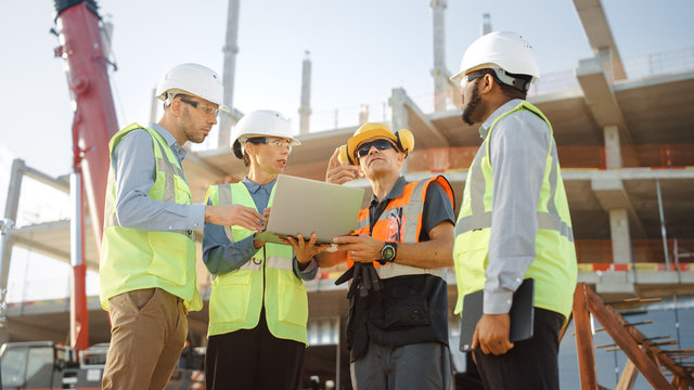Diverse Team of Specialists Use Laptop Computer on Construction Site. Real Estate Building Project with Machinery: Civil Engineer, Investor, Businesswoman and Builder Discussing Blueprint Plan