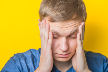 Fototapeta premium Portrait of young naked man closed face by two hands isolated on yellow background