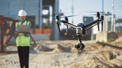 Specialist Controlling Drone on Construction Site. Architectural Engineer or Inspector Fly Drone on Building Construction Site Controlling Quality. Focus on Drone