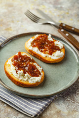 Fototapeta na wymiar Canape or crostini with toasted baguette, cottage cheese, fig jam