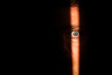 A person's face that has only partially been lit up due to looking through a crack in a doorway....