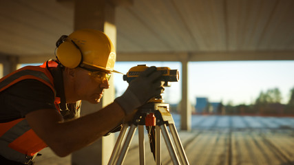 Inside of the Commercial / Industrial Building Construction Site: Engineer Surveyor Takes Measures...