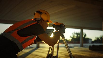 Inside of the Commercial / Industrial Building Construction Site: Engineer Surveyor Takes Measures...