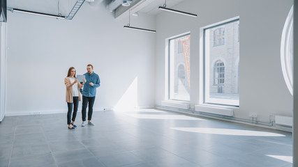 Young Hipster Man and Female Stand in an Empty White Office and Map it with an Augmented Reality...