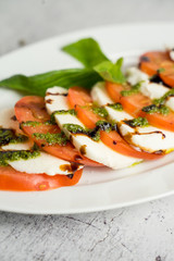 caprese with tomato slices and herbs served with pesto