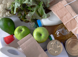 Flat lay from a set of different products on a light surface. Food delivery, self-isolation, gratuitous help concept. Horizontal orientation, top view, selective focus.