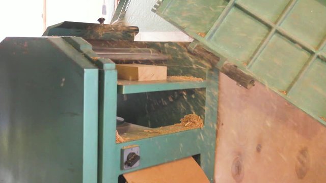 Carpenter is straightens the board's, plank surface on machine, to make them in parallel.