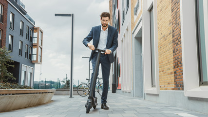 Young Businessman in a Suit Starts to Riding on an Electric Scooter. Modern Entrepreneur Uses Contemporary Ecological Transport to Go on an Office Meeting.