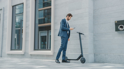 Businessman in a Suit is Activating an Electric Scooter with a Smartphone. He's Scaning the QR Code. Modern Entrepreneur Uses Contemporary Ecological Transport to Go on an Office Meeting.