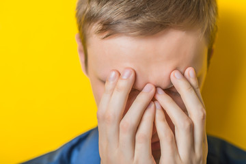 Young man in a blue shirt on a yellow background. showing fatigue, sleepy, sleepy, closes his eyes...