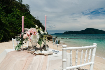 Composition of bright colors on the table. Wedding dinner on the sandy seashore for two.